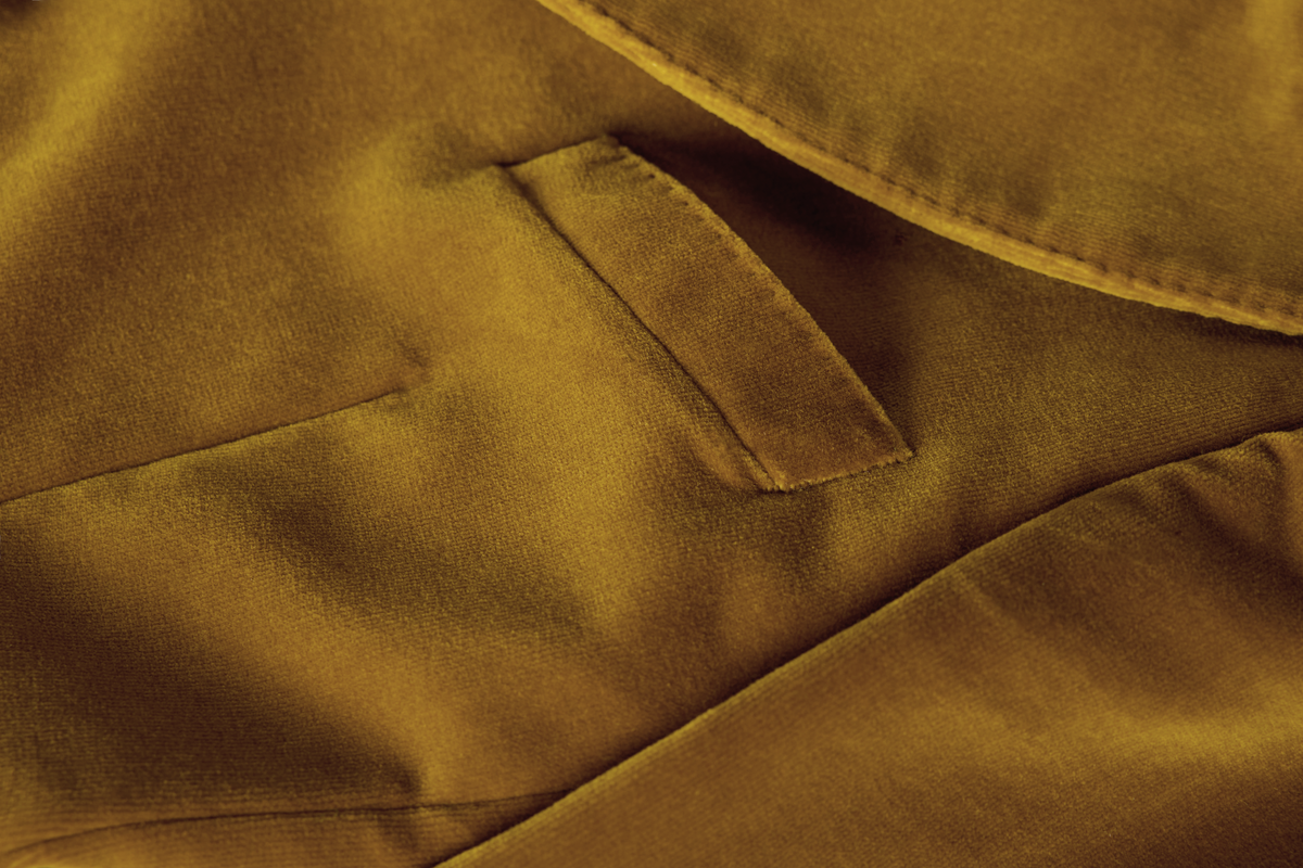 Close-up of a mustard yellow fabric garment showing a pocket and soft textured material.