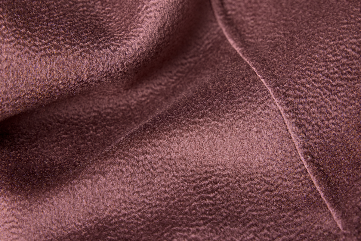 A close-up of draped mauve-brown velvet fabric with a soft, textured surface and a visible seam.
