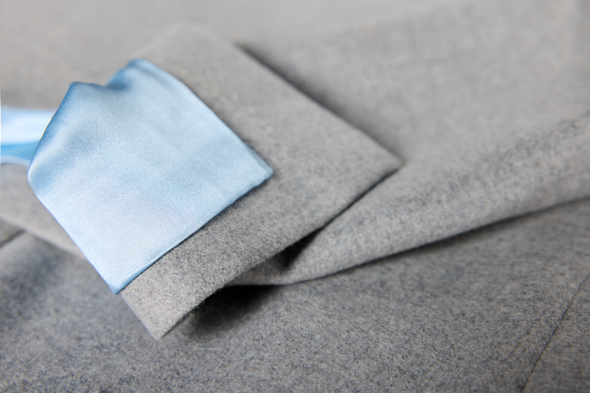 A close-up of a gray suit jacket with a light blue lining.